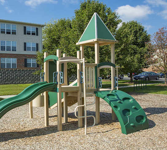 A playground with a green slide and a wooden structure.