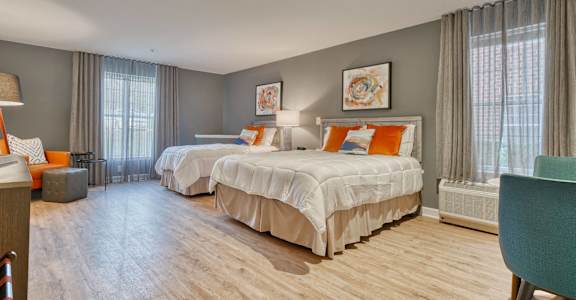 A bedroom with two beds and a chair.