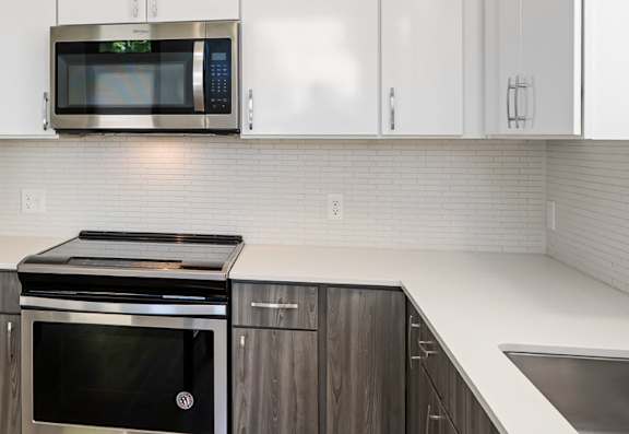A modern kitchen with a white countertop and stainless steel appliances.