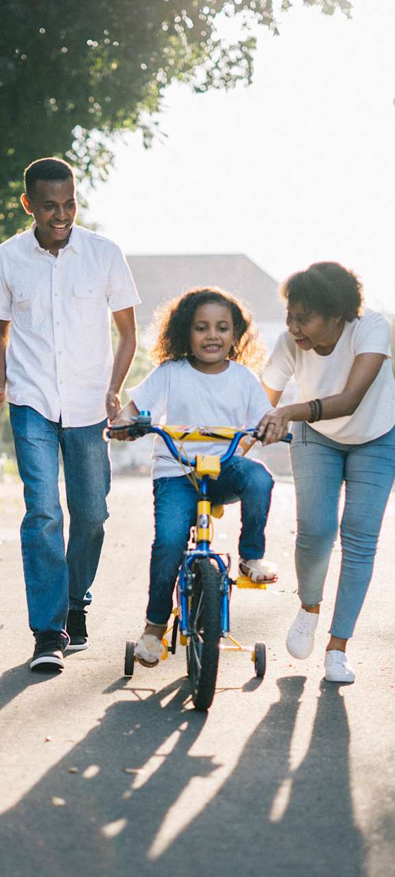 Family of three is walking together in a park with child on bicycle at Signature Pointe, Washington