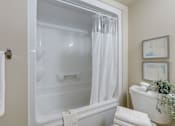 Thumbnail 33 of 33 - A white bathroom with a glass shower door and a white tub.