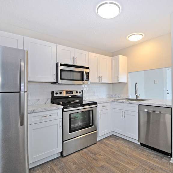 an empty kitchen with stainless steel appliances and white cabinets