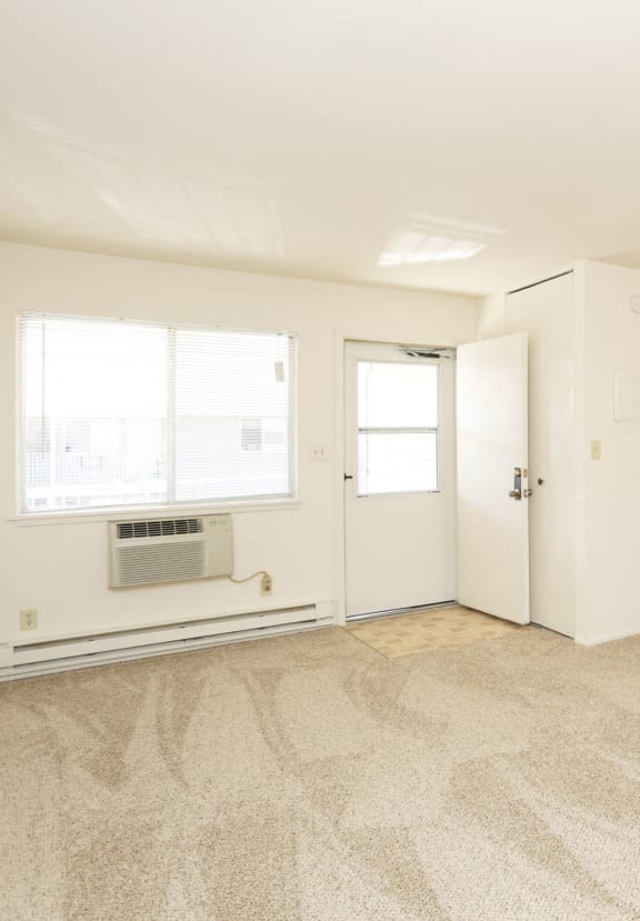 the living room and kitchen of an apartment with white walls and flooring