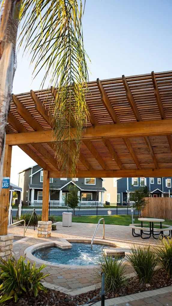 A wooden pergola over a hot tub in a backyard.