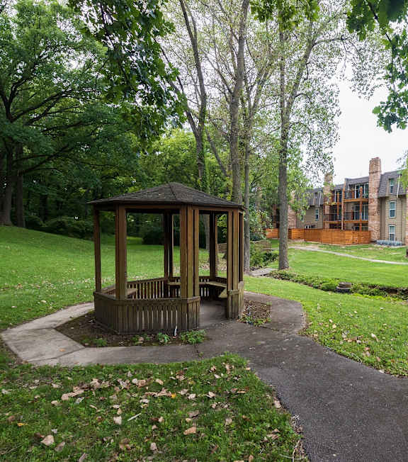 A picturesque gazebo stands in the center of a lush green park within the Tanglewood Apartment Complex.