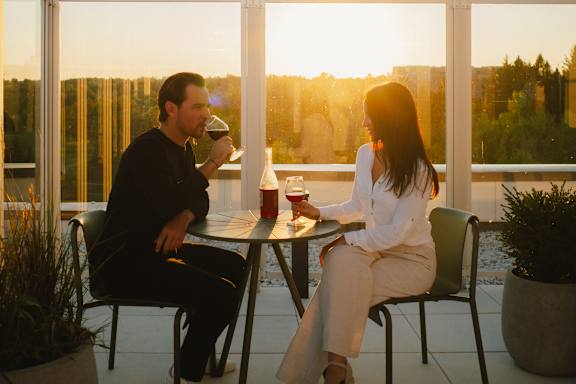 Two people sitting at a table on a balcony during sunset.
