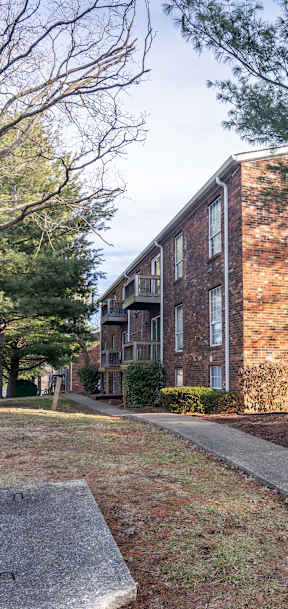 A white car is parked on the street in front of a brick building.