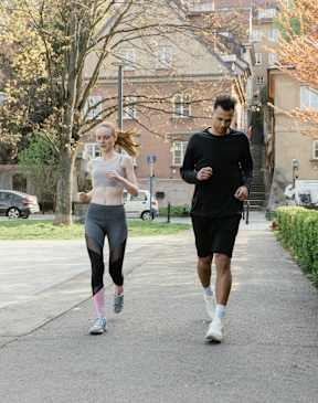 Two people jogging on a path in a park.
