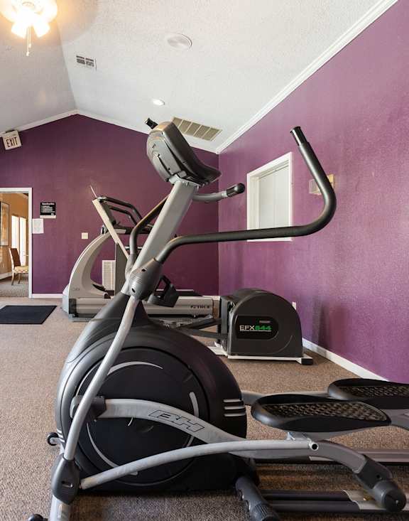 The fitness center at Cedar Crest Apartments featuring cardio machines, strength equipment, and workout space for residents.