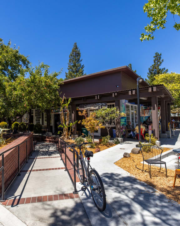 a sidewalk in front of a building with benches and trees