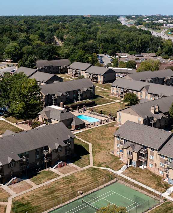 Aerial view of tennis court at Olde English Village surrounded by apartment buildings.