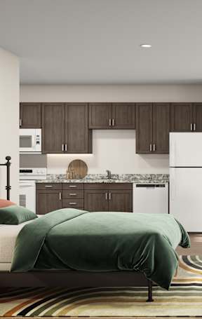 A modern living room with a green couch and a kitchen area in the background.