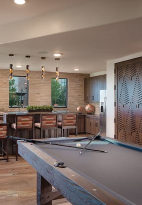 a spacious game room with a pool table and a kitchen with a breakfast bar