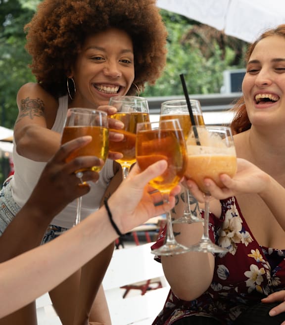 A group of female friends cheers with drinks at a patio restaurant.at 111 Cosburn, Ontario