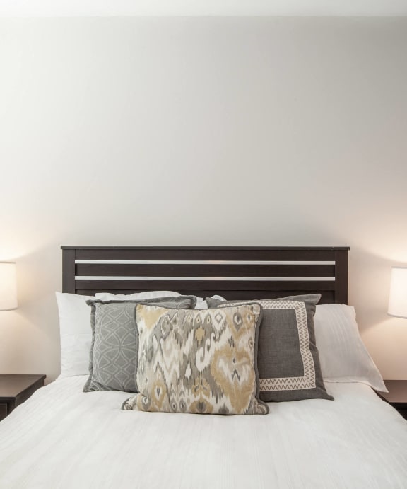 A bedroom with a queen bed and two nightstands and lamps