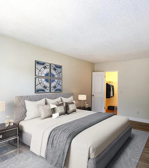 A well-lit bedroom with a large bed and a painting on the wall.
