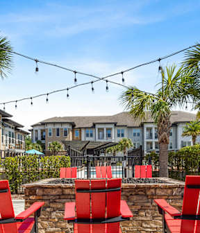 A patio with red chairs and a fire pit.