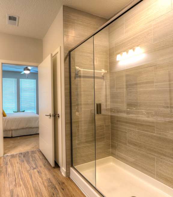 A bathroom with a walk-in shower and a vanity with a marble countertop.