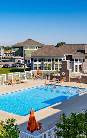 A large swimming pool surrounded by a white fence and trees.