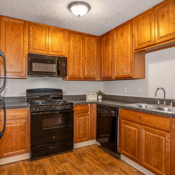 A kitchen with wooden cabinets and a black oven.
