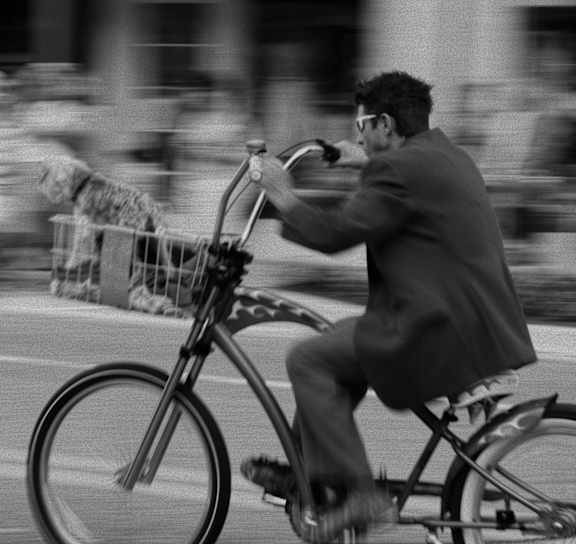 A man in a suit rides a bicycle on a city street.