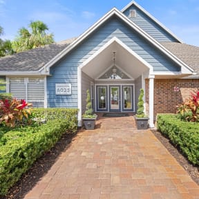 a blue house with a brick pathway leading to the front door