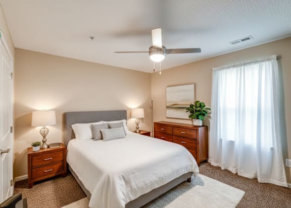A bedroom with a bed, nightstand, and window.