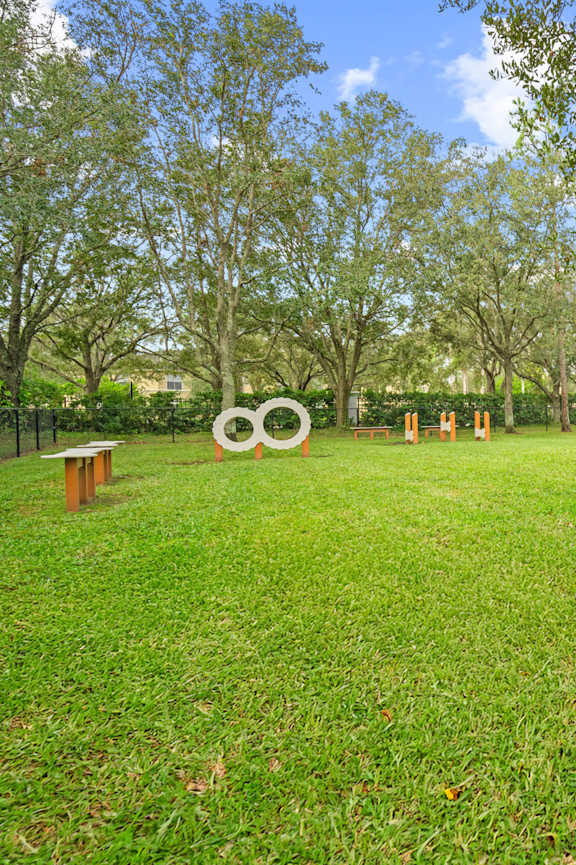 A park with a grassy area and a large sculpture in the middle at The Grand Reserve at Tampa Palms Apartments, Tampa