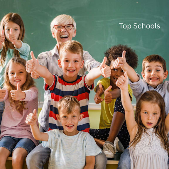 A group of children are giving a thumbs up in front of a blackboard with the words "Top Schools" written on it.