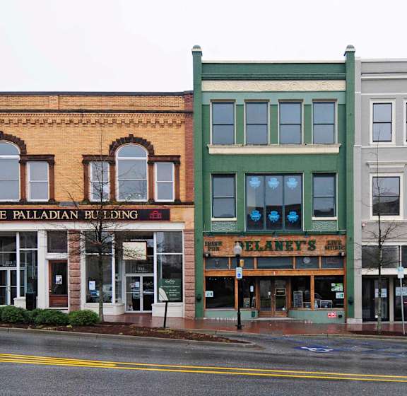 Three storefronts on a street corner with a sign that says "The Palladian Building".