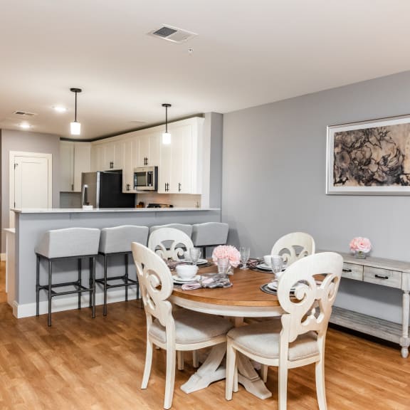 a dining area with a table and chairs and a kitchen in the background