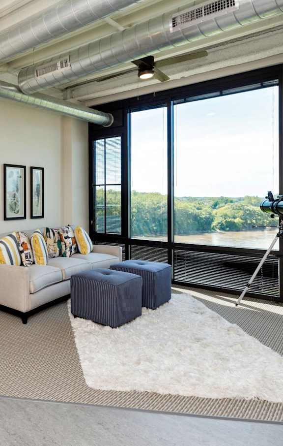 a living room with a couch and a desk and a large window at City Square Lofts, Des Moines, IA 50309