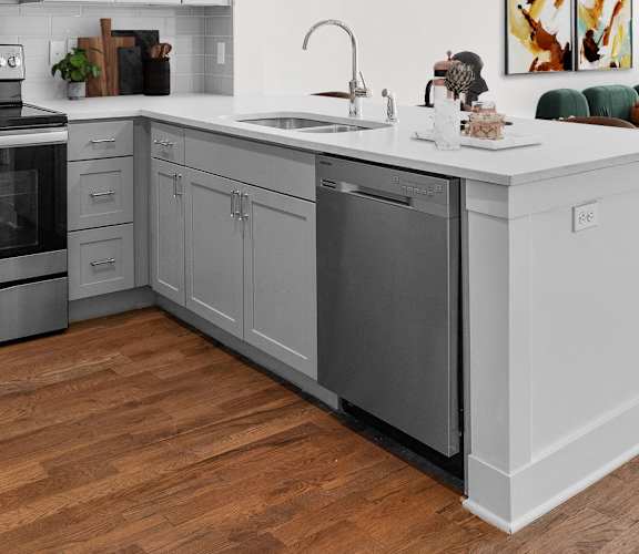 A modern kitchen with wooden floors and stainless steel appliances.