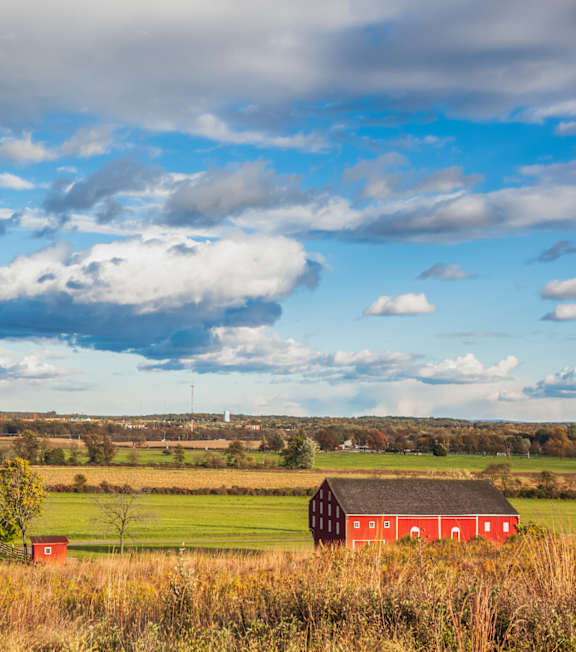 A farm with red barns and a blue barn in the distance.
