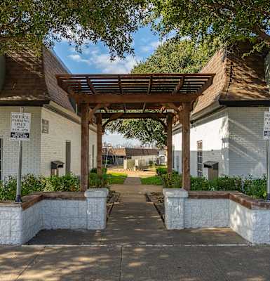 the outside of a white building with an arch and trees