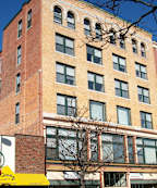 A tall red brick building with many windows.