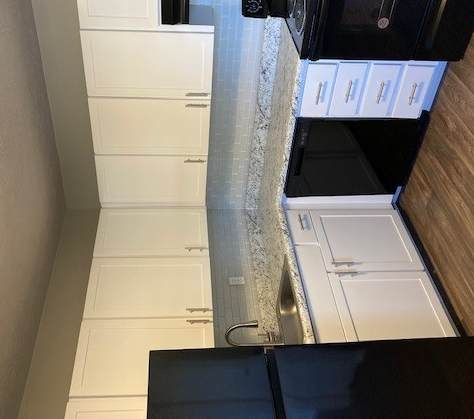 a kitchen with white cabinets and black appliances