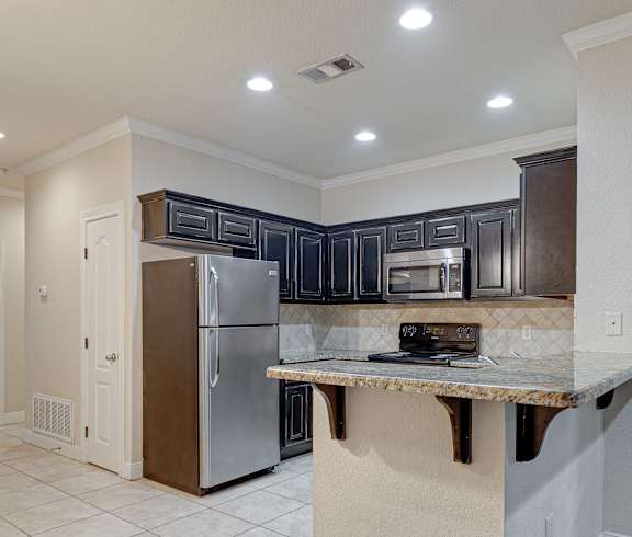 A kitchen with a refrigerator, microwave, and oven. at Logan Ridge Apartments, Apartments, San Marcos, TX