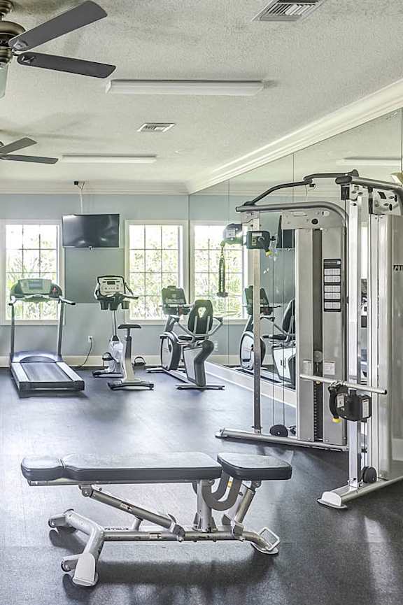 A spacious gym with a variety of equipment including treadmills, weight machines, and benches at Heritage Cove Apartments in Stuart, FL, 34997