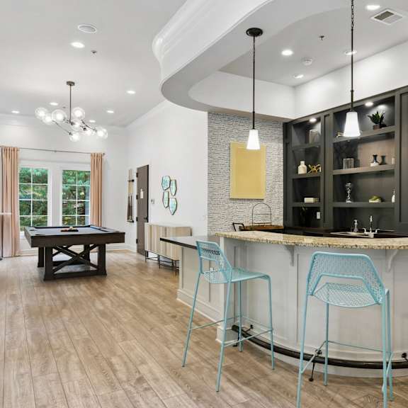A modern bar area with a curved counter and blue chairs.