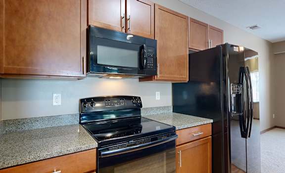 a kitchen with black GE appliances and granite counter tops