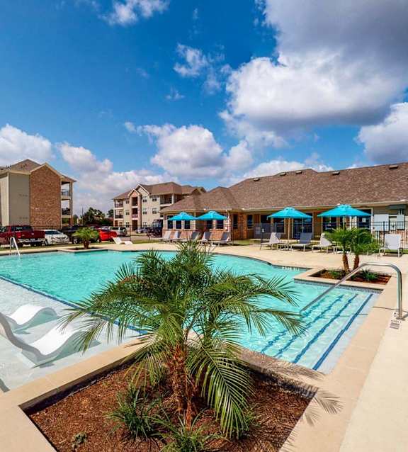 A pool surrounded by palm trees and umbrellas.