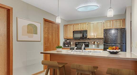 an updated kitchen with black appliances and wood cabinets