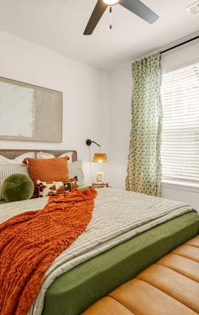 A bedroom with a bed, a bench, and a ceiling fan.