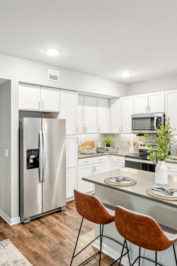 A kitchen with a white fridge, white cabinets, and a white counter at Edge75, Naples, Florida 34104