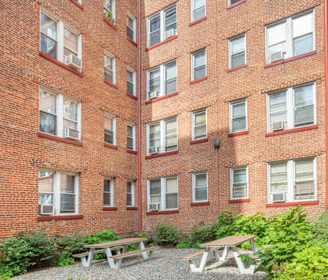 a brick apartment building with a courtyard and picnic tables