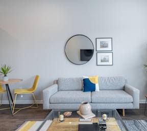 A living room with a glass coffee table and a white couch.