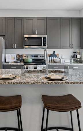 a kitchen with a large island with two chairs and a refrigerator at Nook Nine in Indianapolis, IN