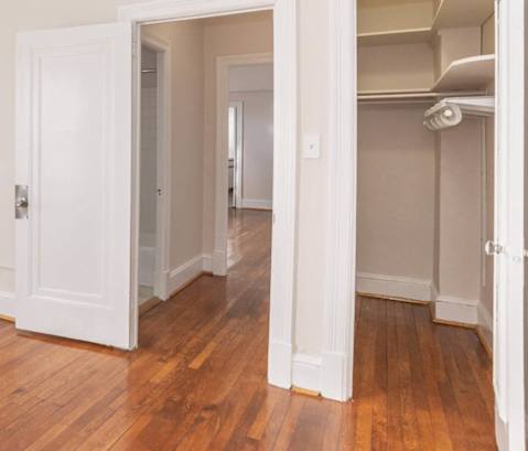 a living room with a hard wood floor and a door to a closet