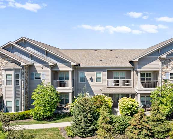 The exterior of an apartment building at Stonepost Crossing, with private fenced-in balconies overlooking a beautiful, lush green landscape.
